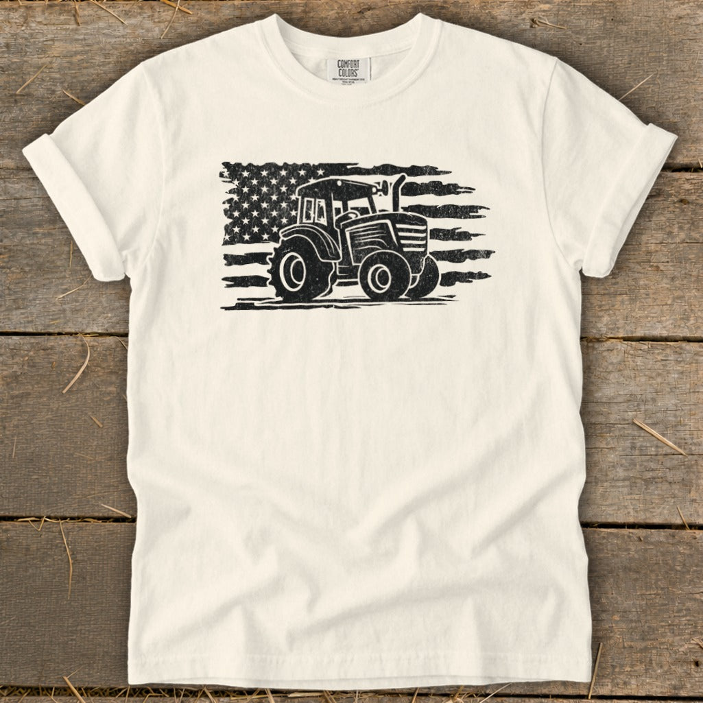 Cream t-shirt with black distressed tractor graphic superimposed on American flag.