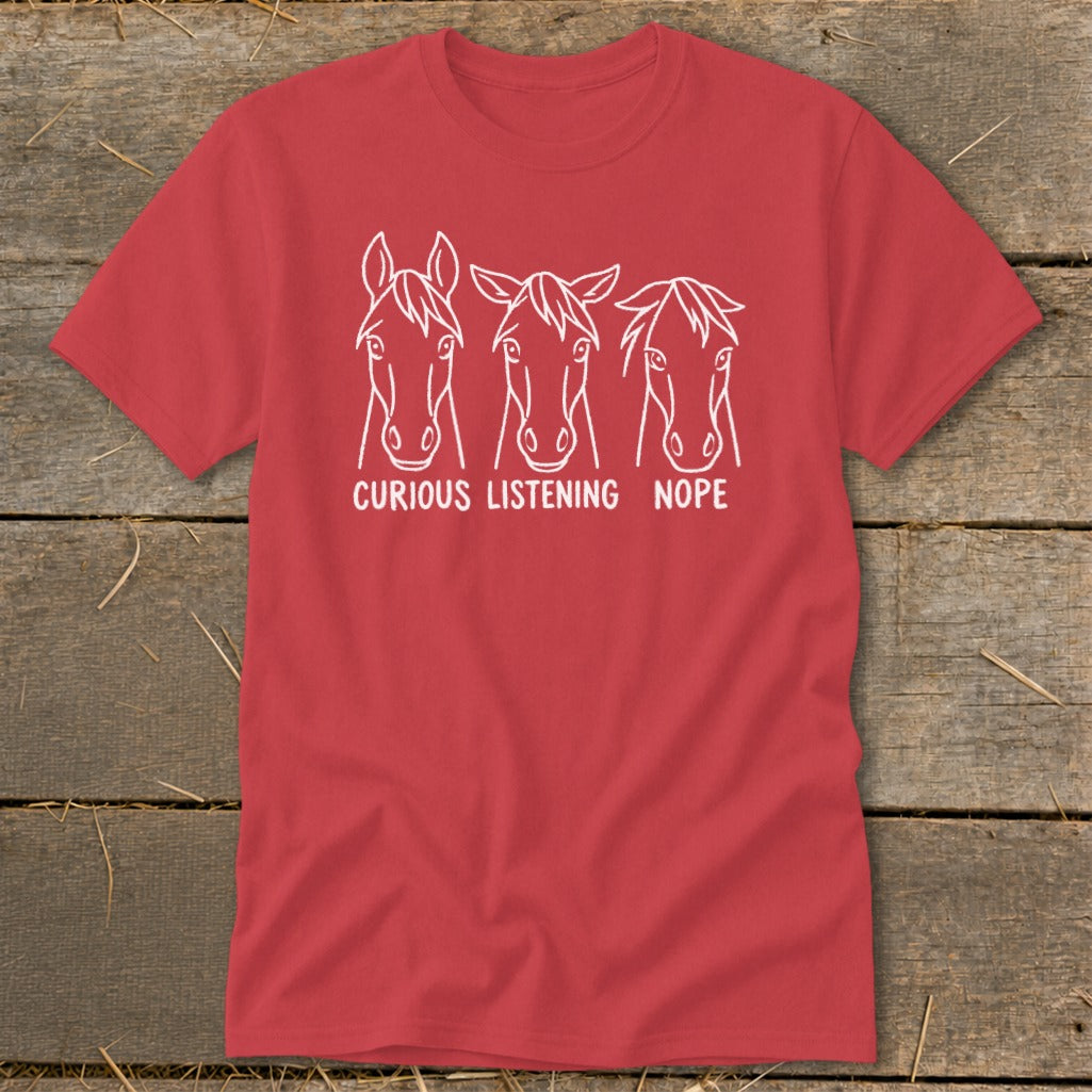 A red short-sleeved t-shirt features three white horse heads with the captions "CURIOUS," "LISTENING," and "NOPE."