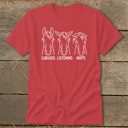 A red short-sleeved t-shirt features three white horse heads with the captions "CURIOUS," "LISTENING," and "NOPE."
