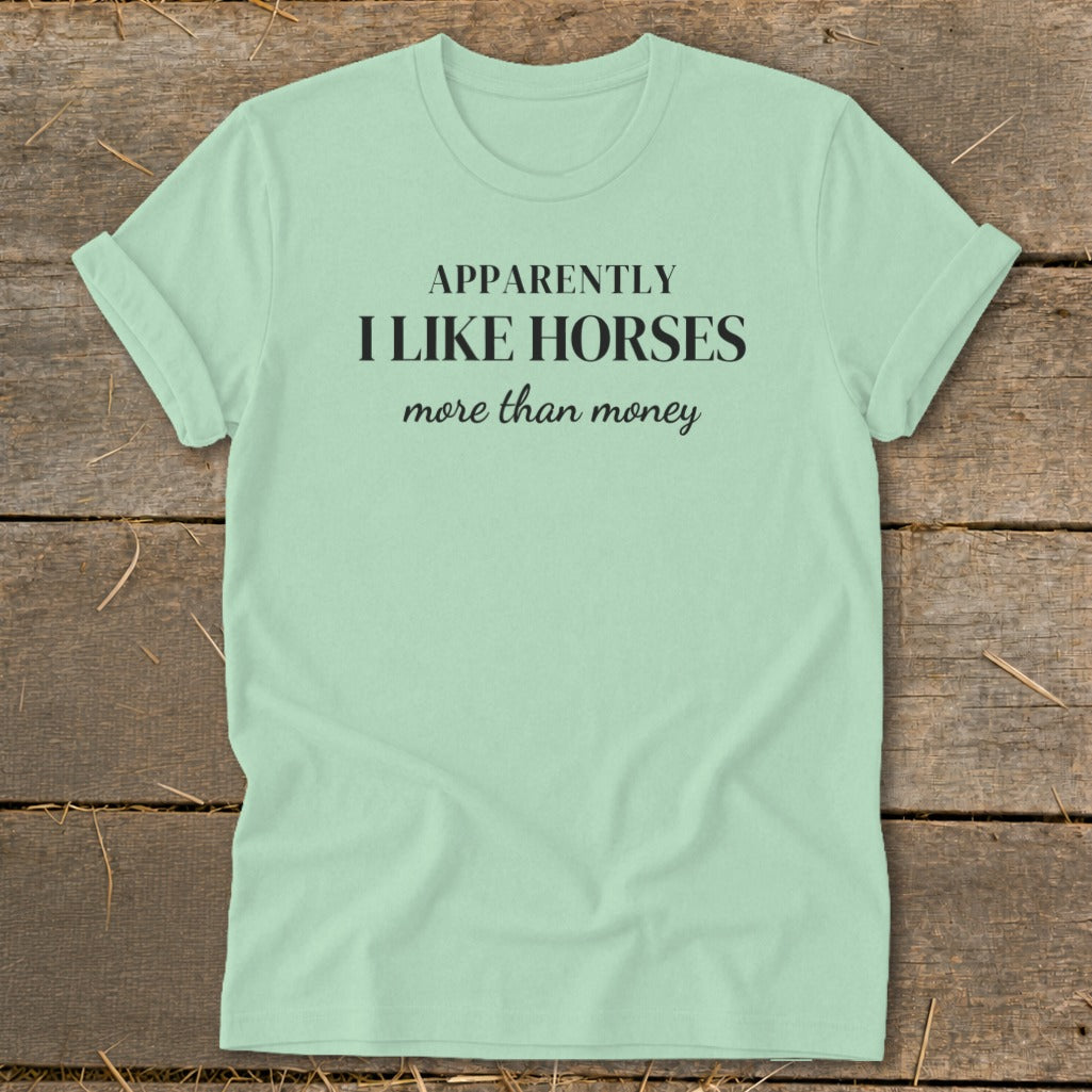 Mint green t-shirt with black text that reads "APPARENTLY I LIKE HORSES more than money."
