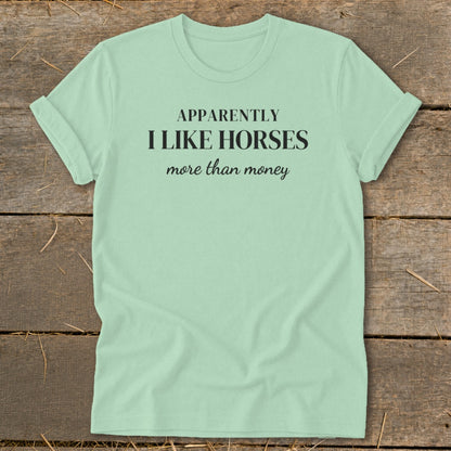 Mint green t-shirt with black text that reads "APPARENTLY I LIKE HORSES more than money."
