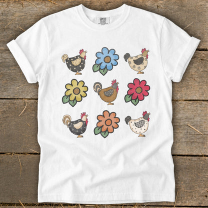 White t-shirt with a print of nine whimsical chickens and flowers.