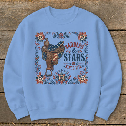 Light blue sweatshirt with graphic of saddle, flowers, and text "Saddles & Stars Since 1776".
