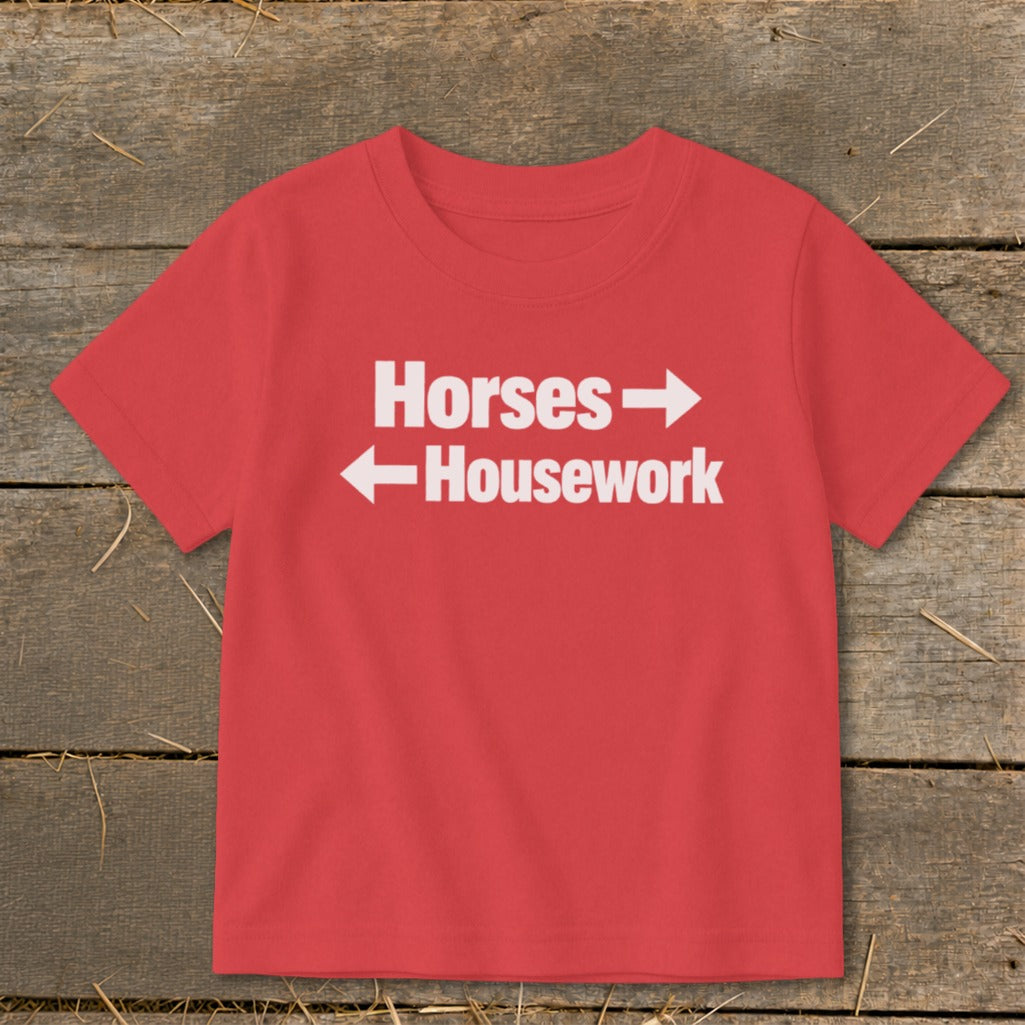A red short-sleeved t-shirt with white text reading Horses with a right arrow and Housework with a left arrow.