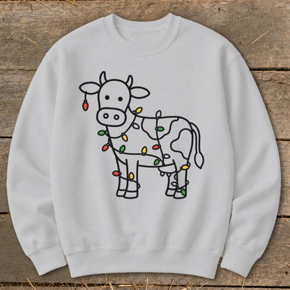Light gray sweatshirt with a black outline drawing of a cow wrapped in colorful Christmas lights.