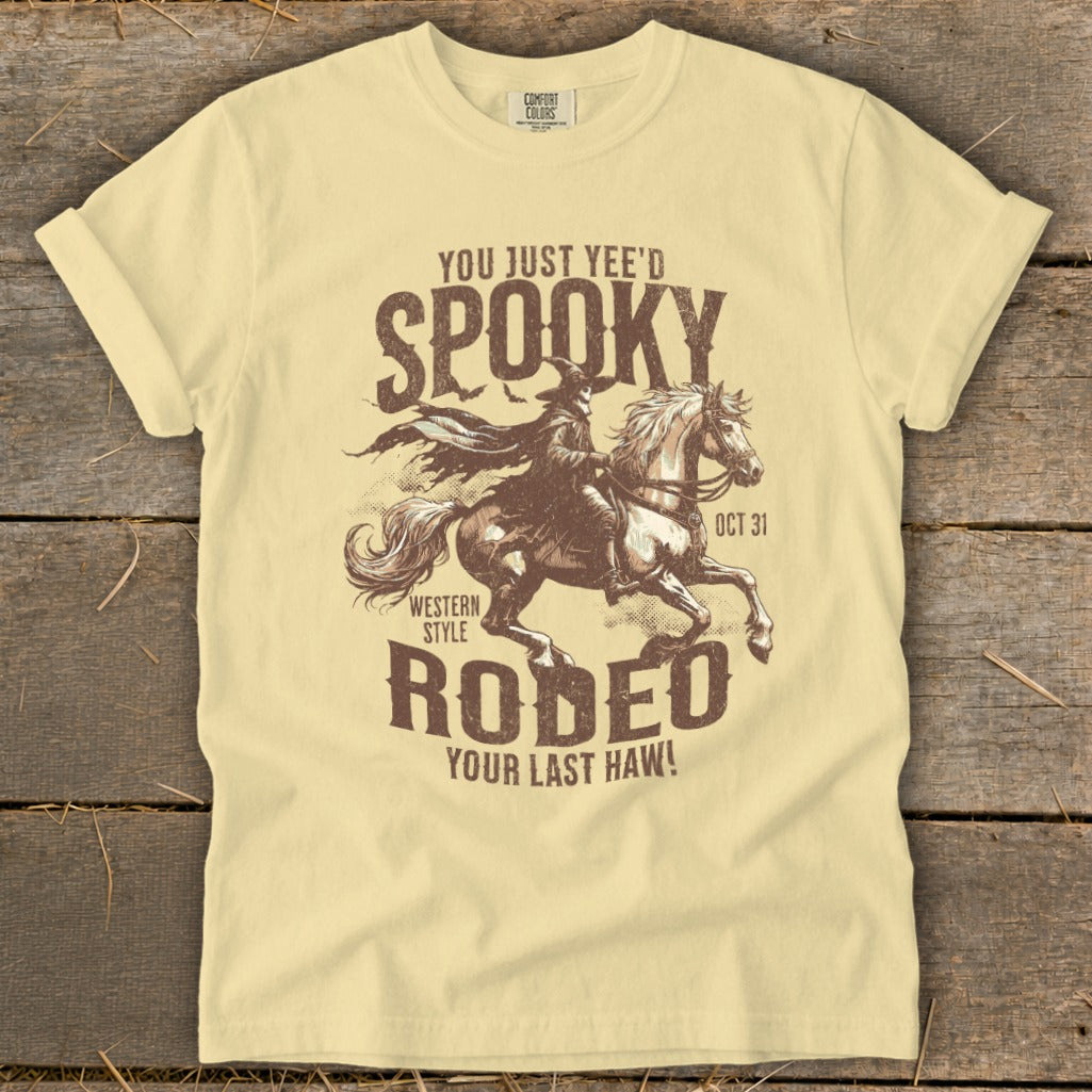 Pale yellow t-shirt with "Spooky Rodeo" graphic of a grim reaper on horseback.