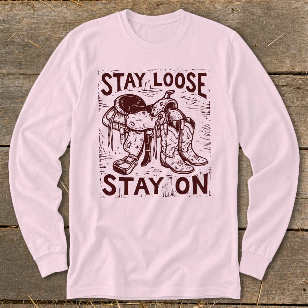 Long sleeve shirt with a cowboy saddle and boots graphic and text "STAY LOOSE STAY ON".