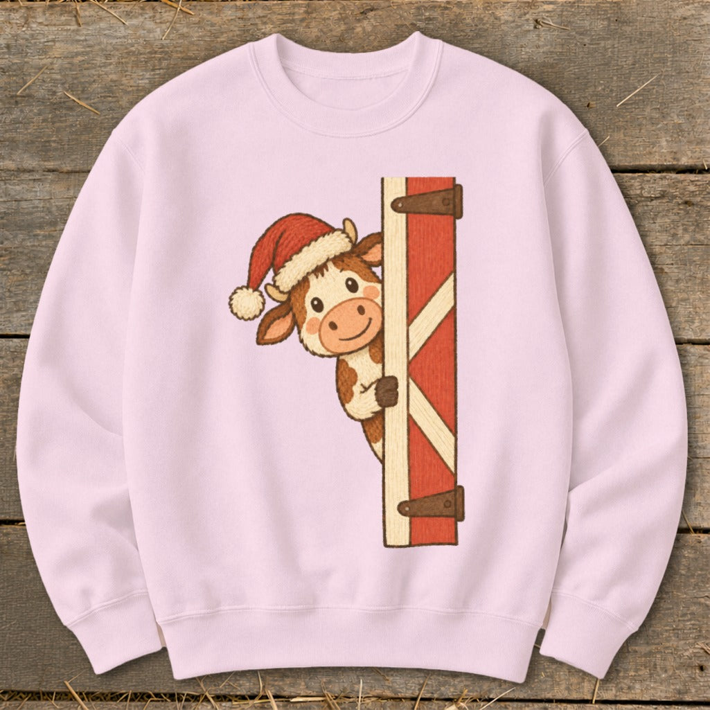 Pink sweatshirt with a cartoon cow wearing a Santa hat peeking from behind a red barn door.