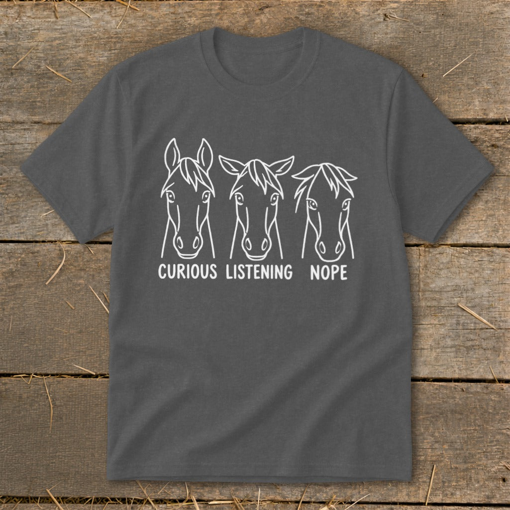 A dark gray crewneck t-shirt featuring three white horse head line drawings with the text curious, listening, and nope underneath each.