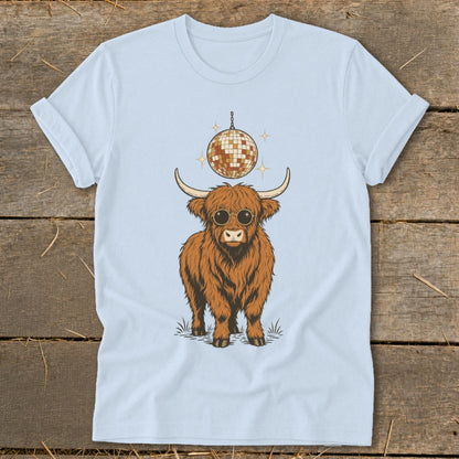 Highland cow with sunglasses and disco ball graphic on a light blue t-shirt.