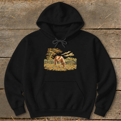 Black hoodie with a painting of a brown and white horse grazing in a field.