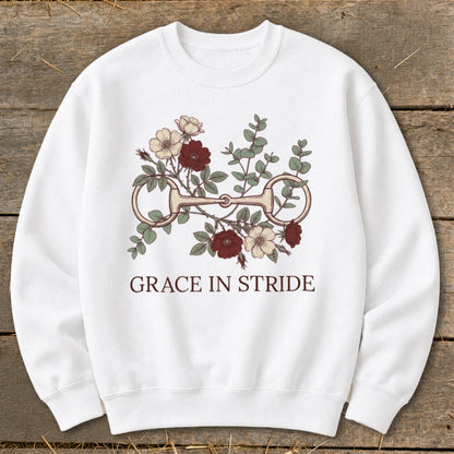 White sweatshirt with a floral horse bit graphic and text "GRACE IN STRIDE."