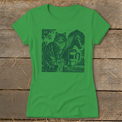 Green t-shirt with a linocut style print of a cat, horse, and mug on a farm.