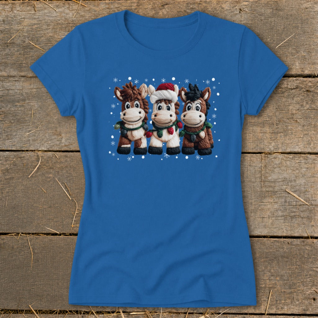Blue t-shirt with a Christmas-themed graphic of three cartoon horses wearing scarves and a Santa hat.