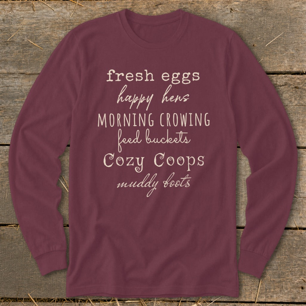 Maroon long-sleeve t-shirt with text: "fresh eggs happy hens MORNING CROWING feed buckets Cozy Coops muddy boots".