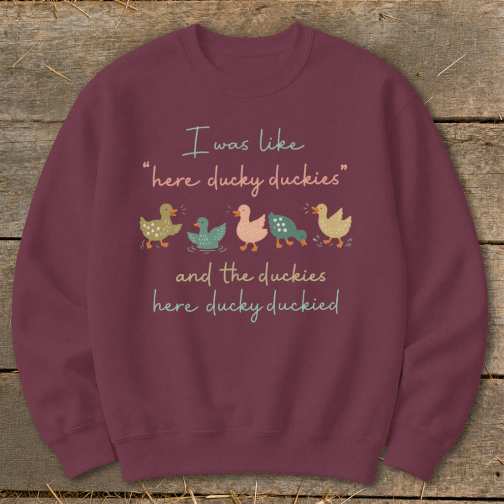 Burgundy sweatshirt with cartoon ducks and text "I was like 'here ducky duckies' and the duckies here ducky duckied".