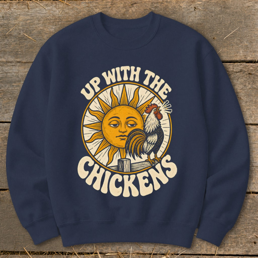 A navy blue crewneck sweatshirt featuring a graphic of a rooster, a smiling sun, and the text Up With The Chickens.
