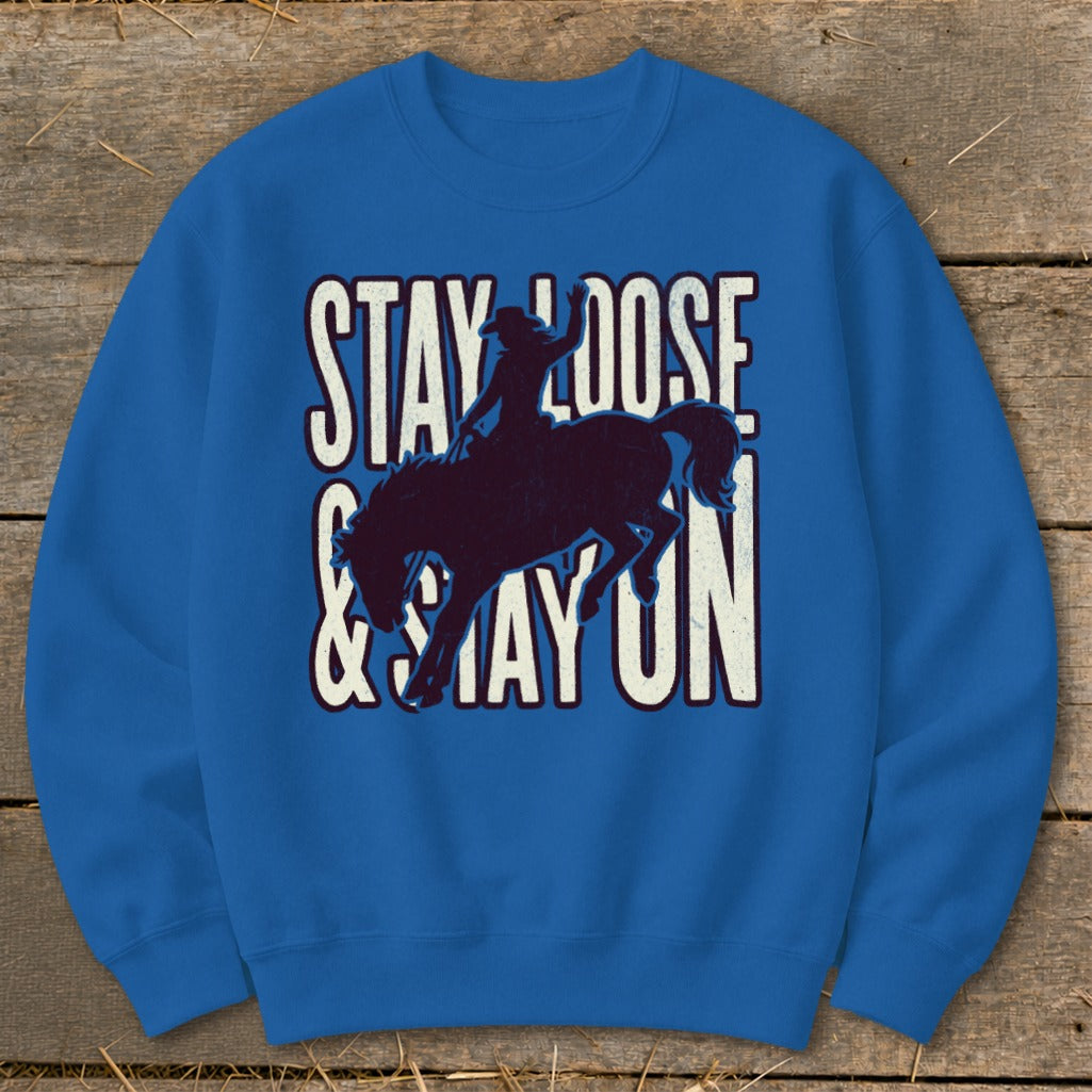 Blue sweatshirt with cowboy on bucking horse graphic and "Stay Loose & Stay On" text.