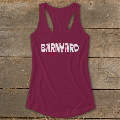 Maroon women's racerback tank top with distressed white text reading BARNYARD laid on a rustic wooden background.