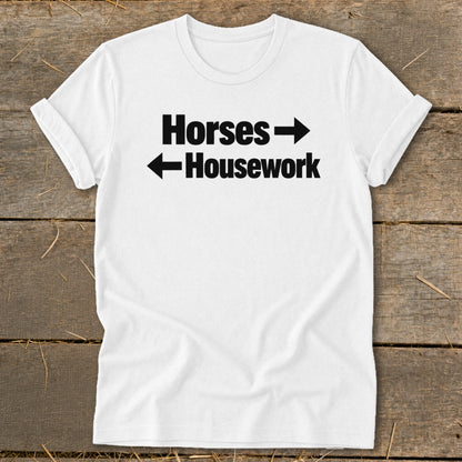 A white t-shirt with black text that reads "Horses" pointing right and "Housework" pointing left.
