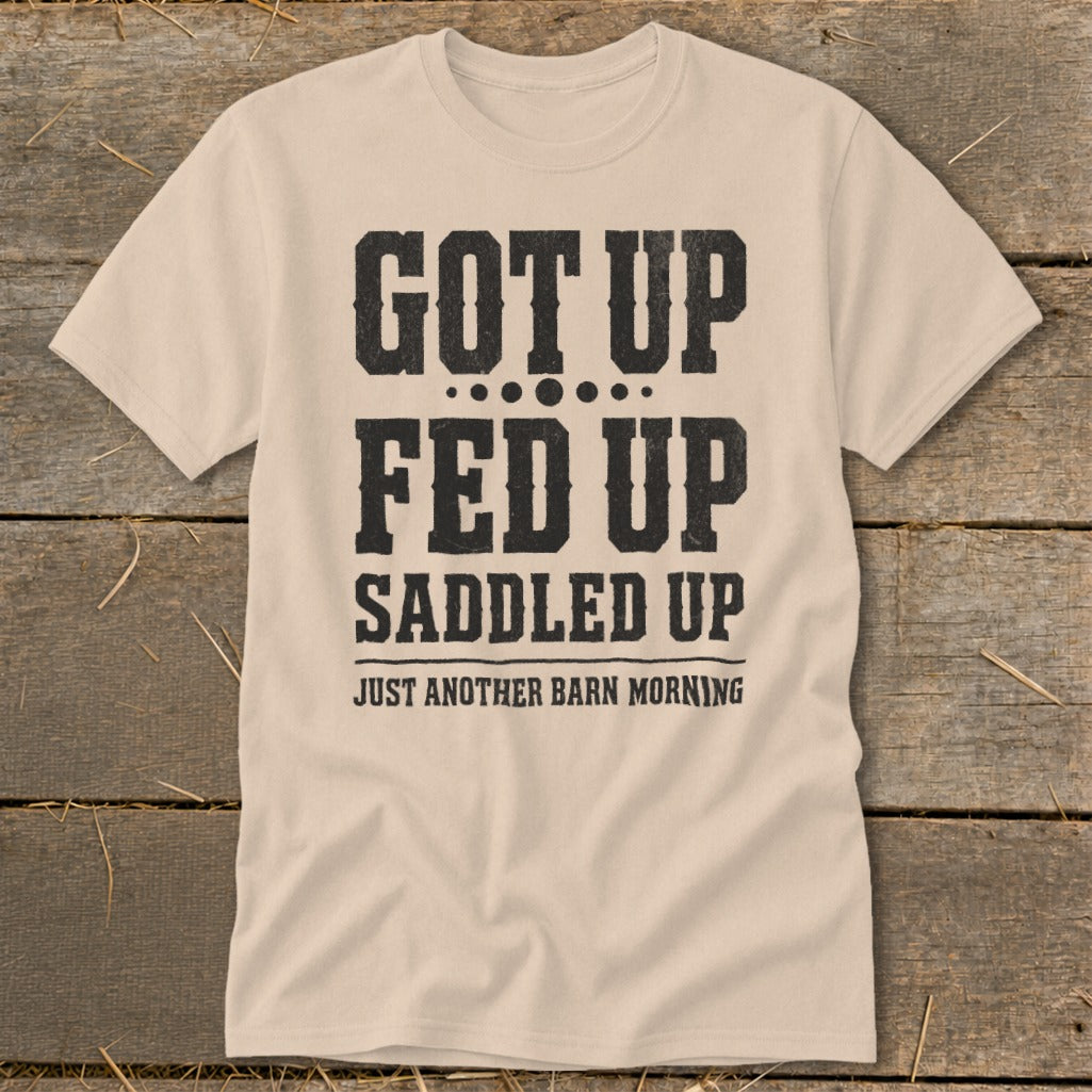 Light beige t-shirt with black text reading "GOT UP FED UP SADDLED UP JUST ANOTHER BARN MORNING".