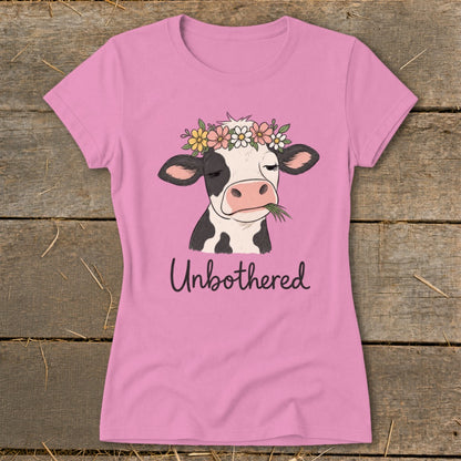 Pink t-shirt with a cow wearing a flower crown and text "Unbothered".