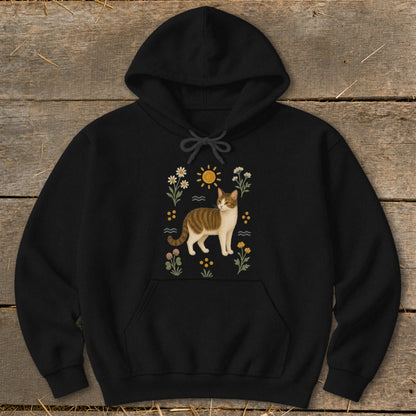 Black hoodie with a tabby cat among flowers and a sun illustration.