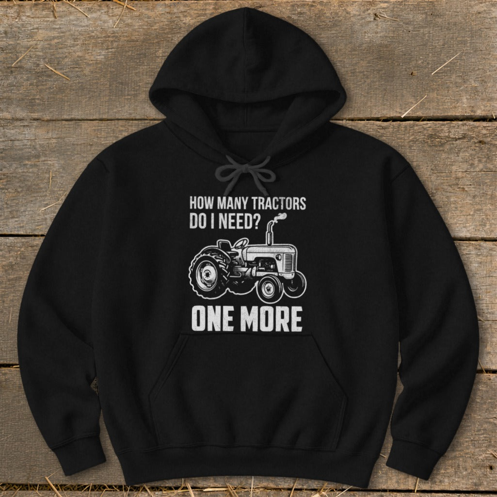 Black hoodie with graphic "How Many Tractors Do I Need? One More" and tractor illustration.