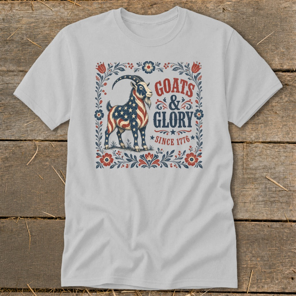 White t-shirt with a goat design featuring American flag stars and stripes, text "GOATS & GLORY SINCE 1776".