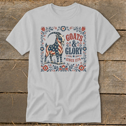 White t-shirt with a goat design featuring American flag stars and stripes, text "GOATS & GLORY SINCE 1776".