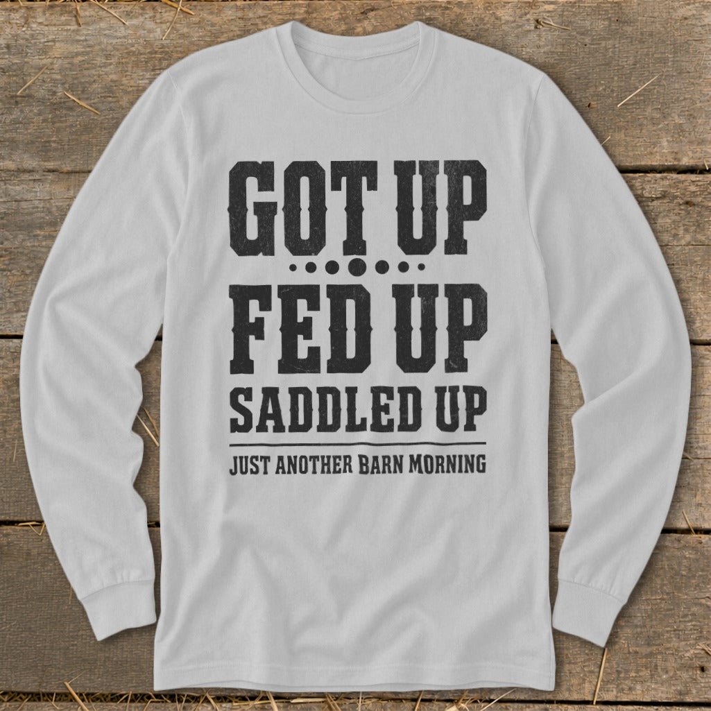 White long sleeve shirt with black distressed text "GOT UP FED UP SADDLED UP JUST ANOTHER BARN MORNING".