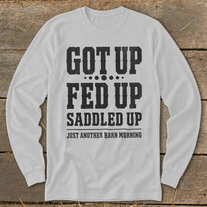 White long sleeve shirt with black distressed text "GOT UP FED UP SADDLED UP JUST ANOTHER BARN MORNING".