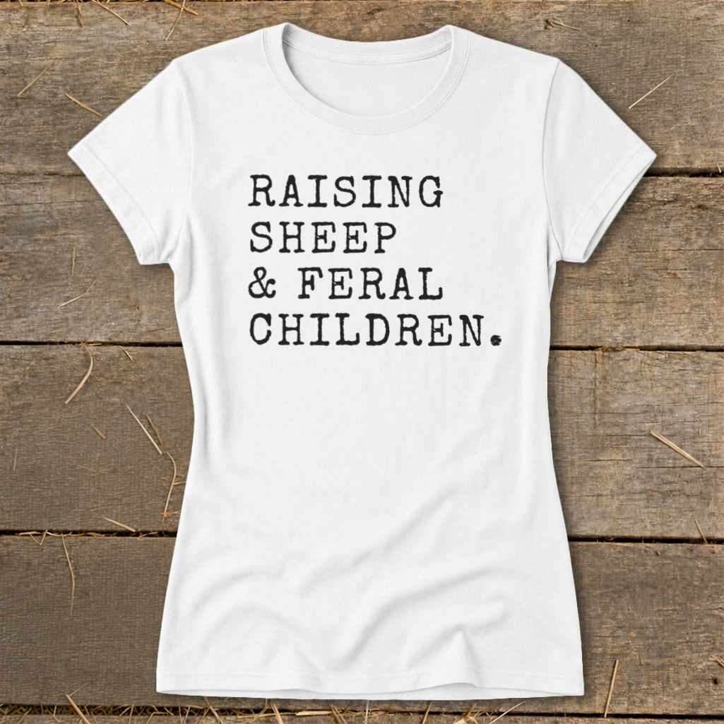 White t-shirt with black typewriter text: "RAISING SHEEP & FERAL CHILDREN."