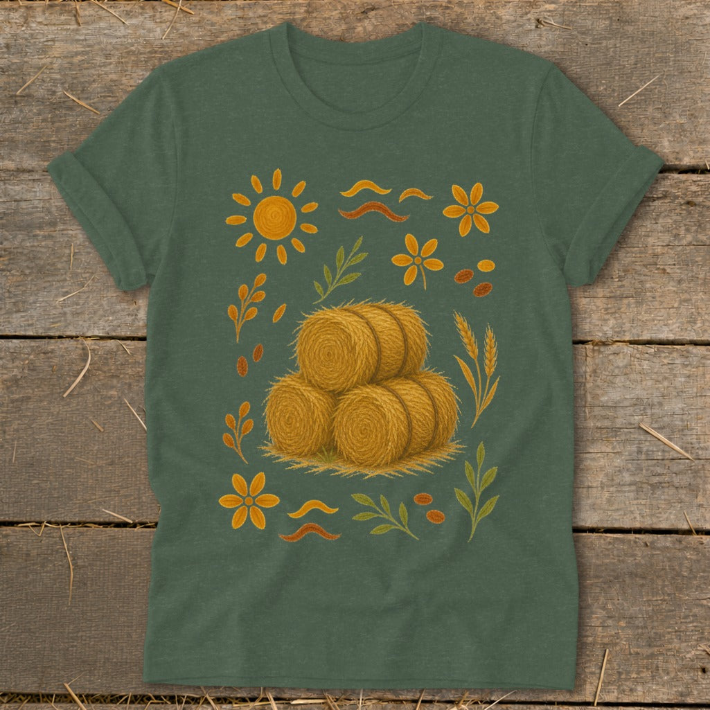Green t-shirt with a design of hay bales, sun, flowers, and wheat stalks.