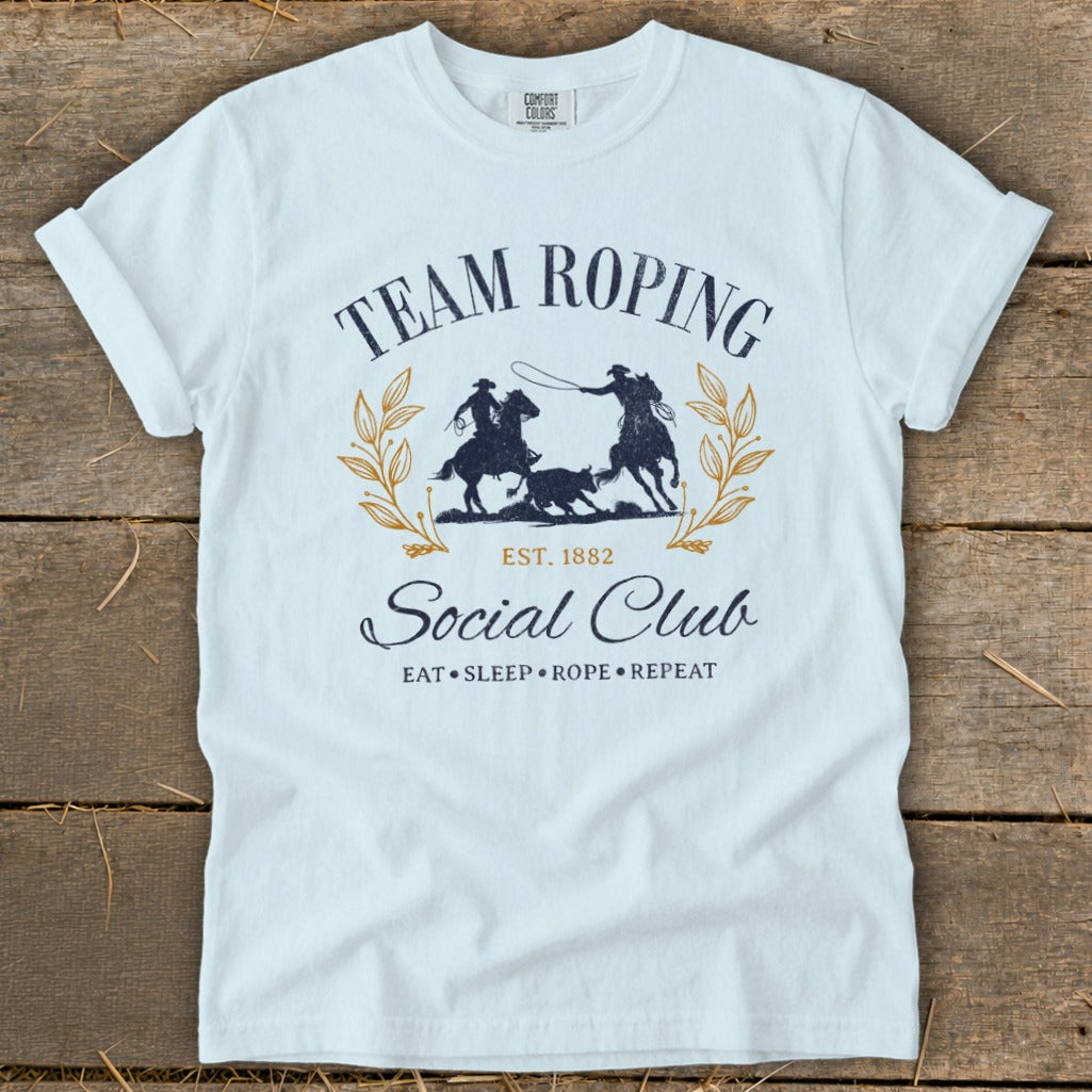 White t-shirt with "Team Roping Social Club" graphic featuring cowboys, horse, and steer.