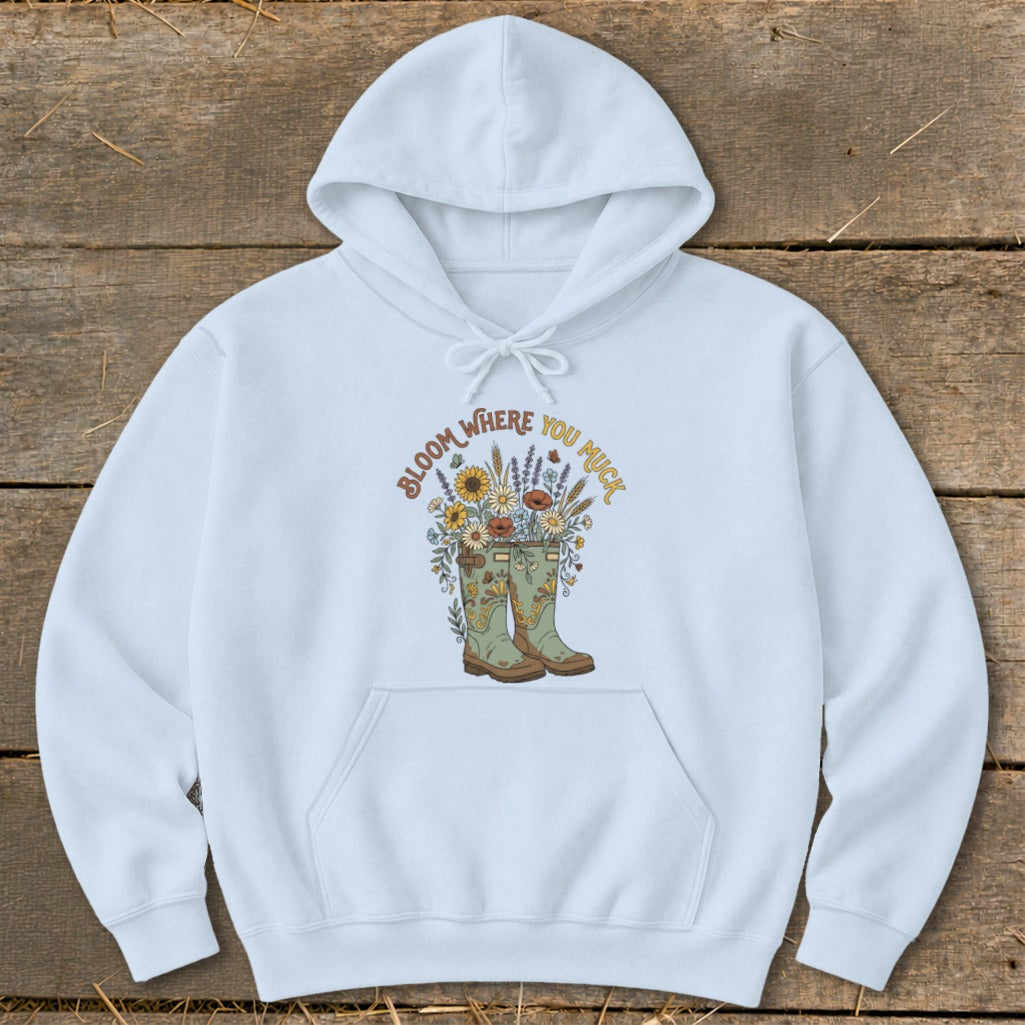 Light blue hoodie with boots and flowers graphic that reads "Bloom Where You Muck".