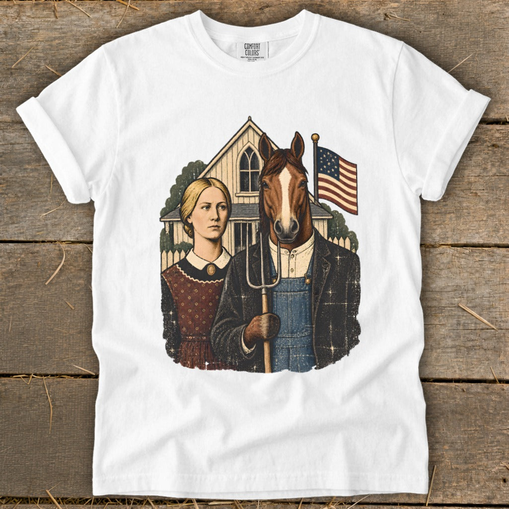 A white short-sleeved t-shirt featuring a graphic parody of American Gothic, showing a woman and a man with a horse head holding a pitchfork.