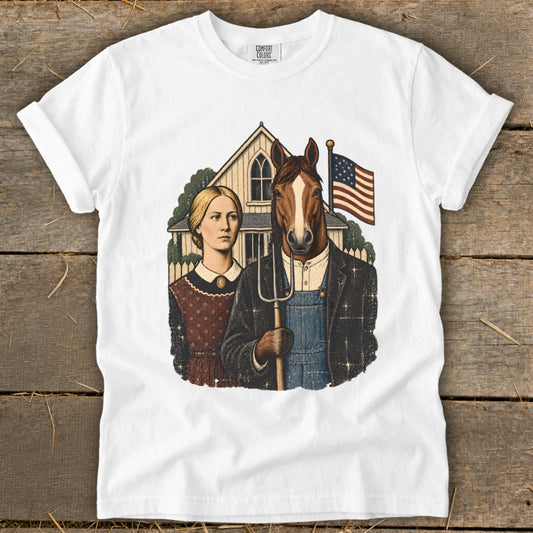 A white short-sleeved t-shirt featuring a graphic parody of American Gothic, showing a woman and a man with a horse head holding a pitchfork.