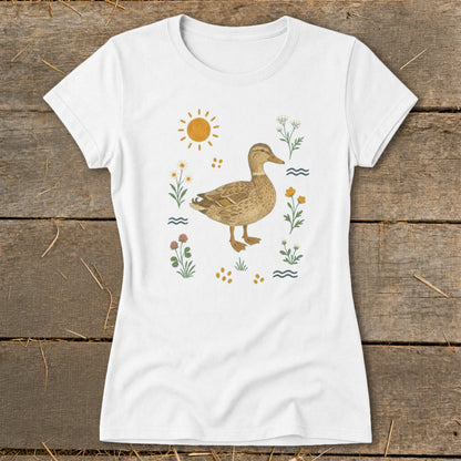 White t-shirt with a brown duck surrounded by wildflowers, sun, and waves.