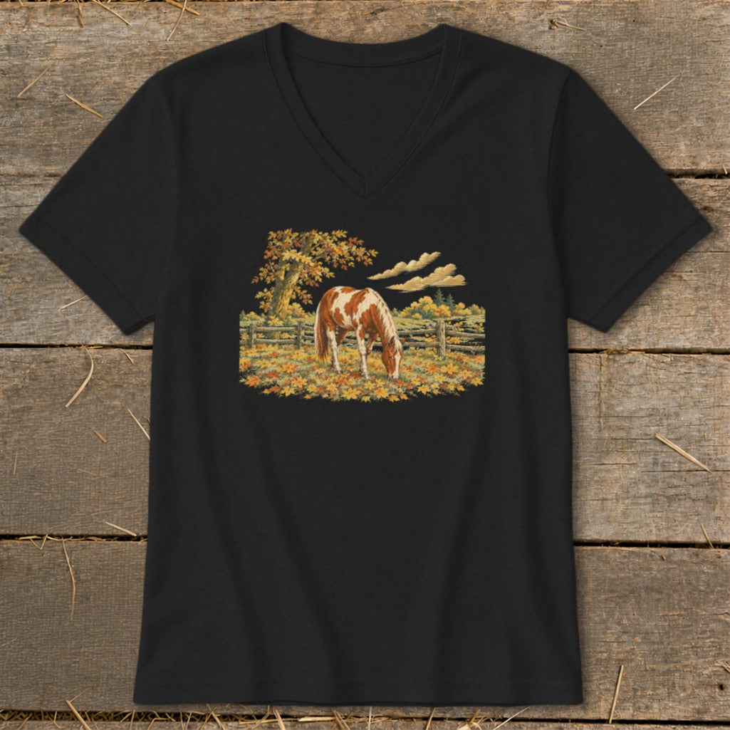 Brown and white horse grazing in a fall pasture with a wooden fence.