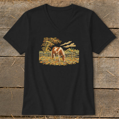 Brown and white horse grazing in a fall pasture with a wooden fence.