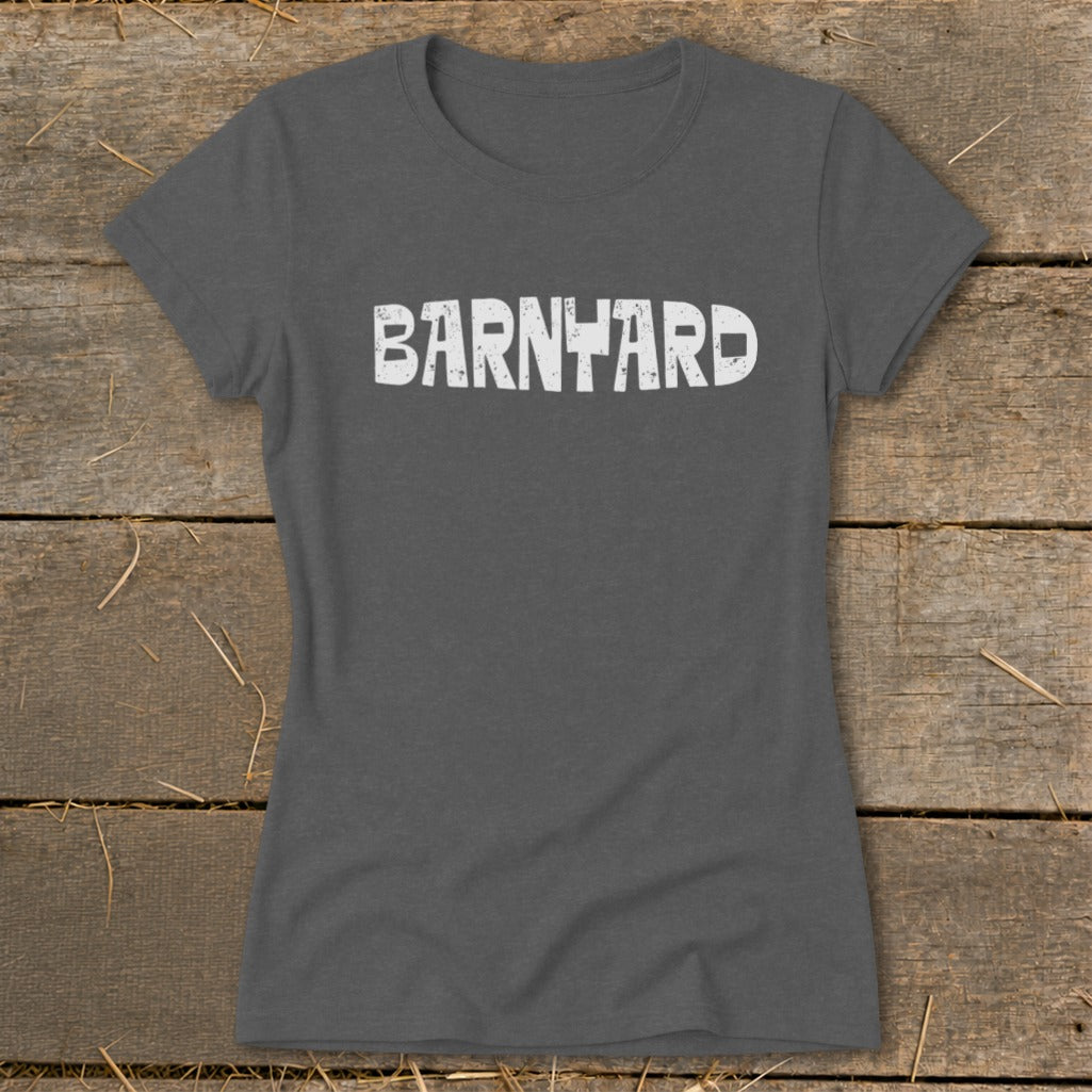 Dark gray short-sleeved t-shirt with distressed white text reading "BARNYARD" centered on the chest, laid flat on rustic wood.