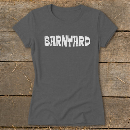 Dark gray short-sleeved t-shirt with distressed white text reading "BARNYARD" centered on the chest, laid flat on rustic wood.