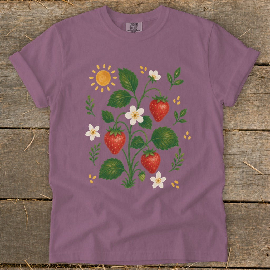 Purple t-shirt with a watercolor strawberry plant, flowers, and sun graphic.