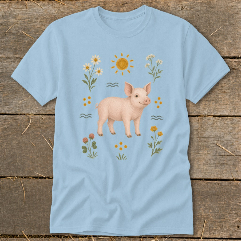 Light blue t-shirt with a drawing of a piglet surrounded by flowers and the sun.