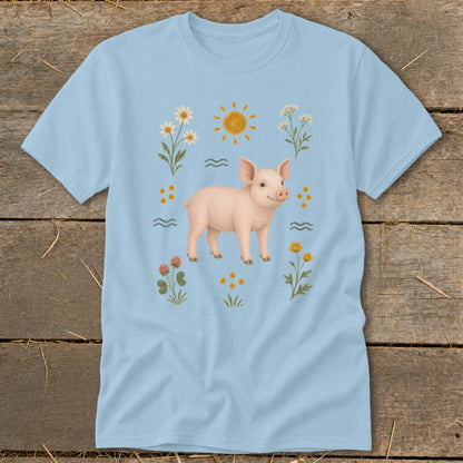 Light blue t-shirt with a drawing of a piglet surrounded by flowers and the sun.