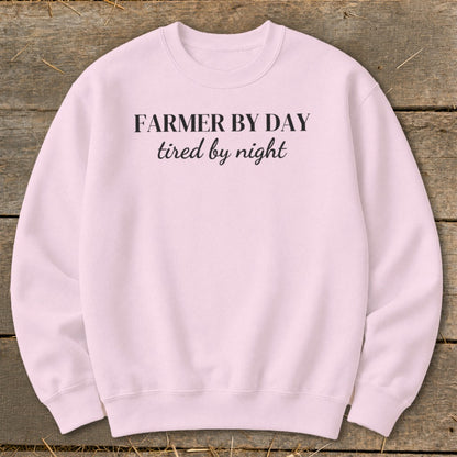 Pink crewneck sweatshirt with black text: "FARMER BY DAY tired by night".