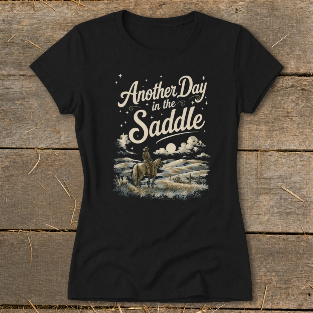 Black t-shirt with "Another Day in the Saddle" text and cowboy on horseback landscape.