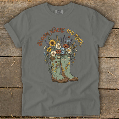 Green boots overflowing with flowers, with "Bloom Where You Muck" text.