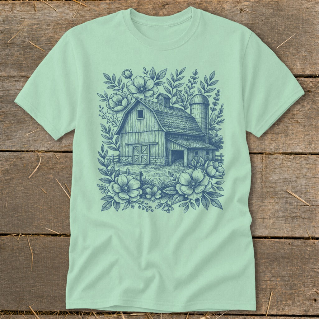 Barn and silo surrounded by floral illustrations on a mint green t-shirt.